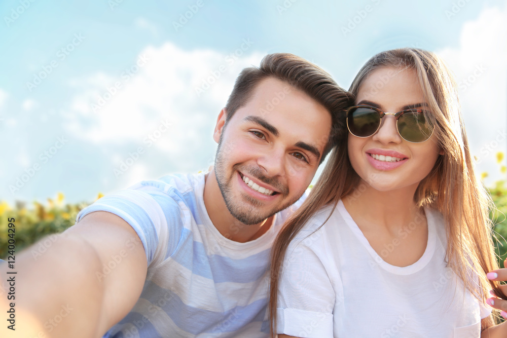 Beautiful young couple making selfie in the sunflowers field