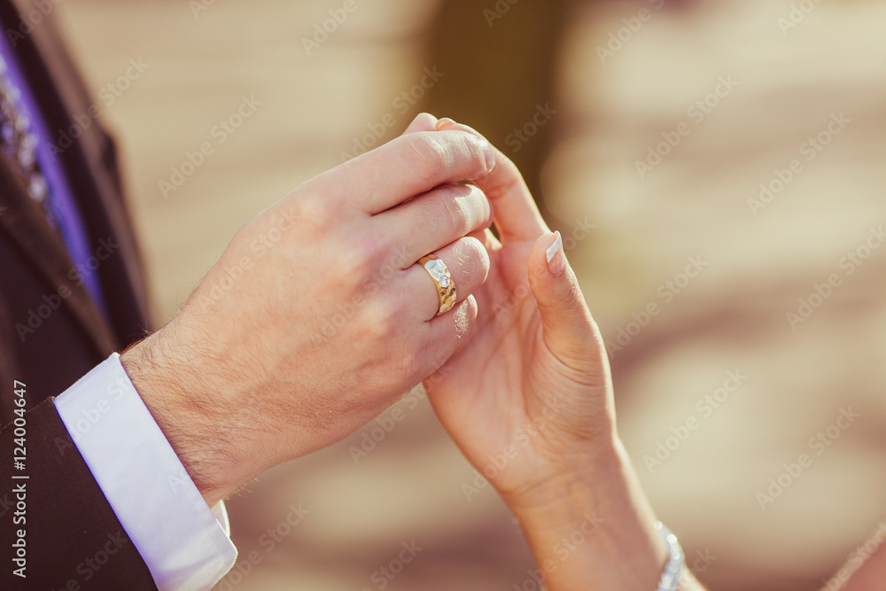 A closeup of groom's hand rouching bride's fingers delicately