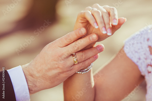 Broad groom s hand touches gently bride s wirst