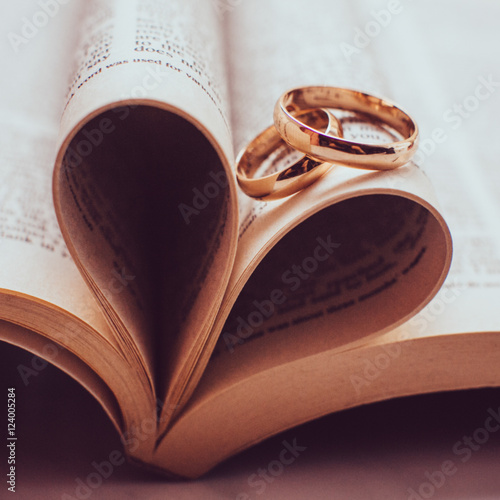 Sparkling wedding rings lie on the book pages