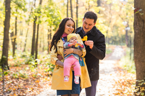happy young family with their daughter spending time outdoor in the autumn park.