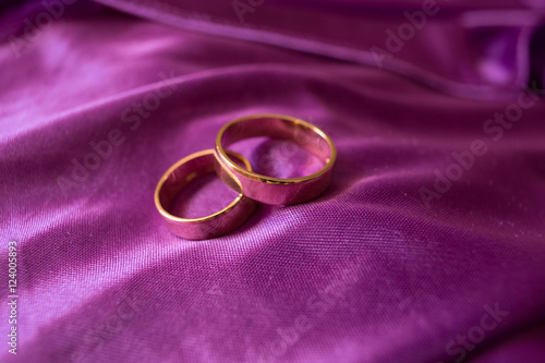 Stunning wedding rings lie on the violet satin