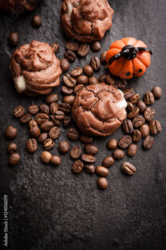Eclairs and coffee beans with halloween decoration on black background