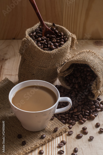 Coffee cup and coffee beans in bag on wooden