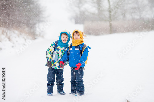 Two little children, boy brothers with backpacks in the park