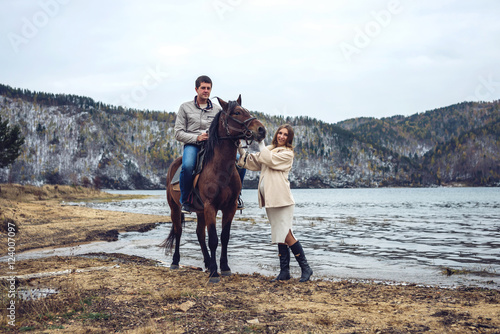 pregnant girl and her husband standing next to the horse