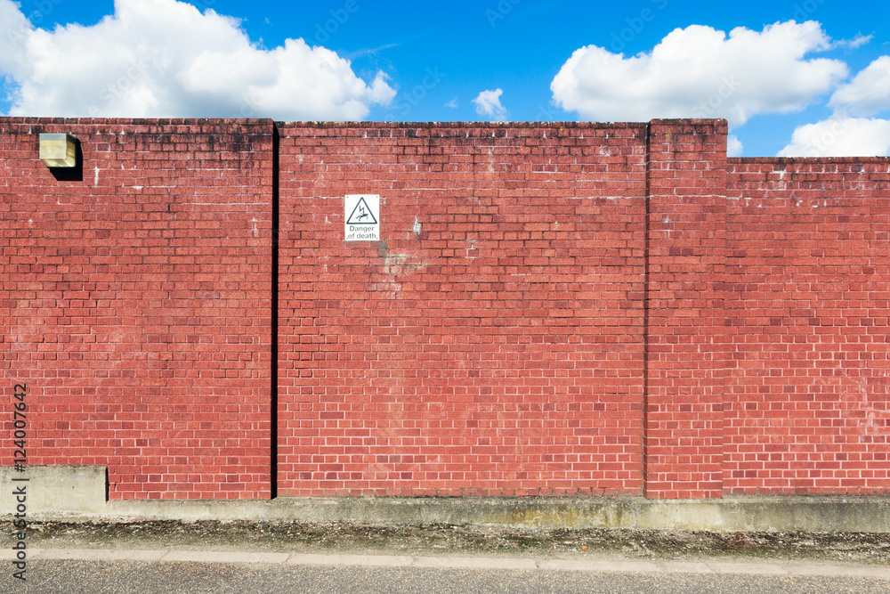 Red brick wall with a warning sign of high voltage danger Red brick wall with a warning sign of high voltage danger