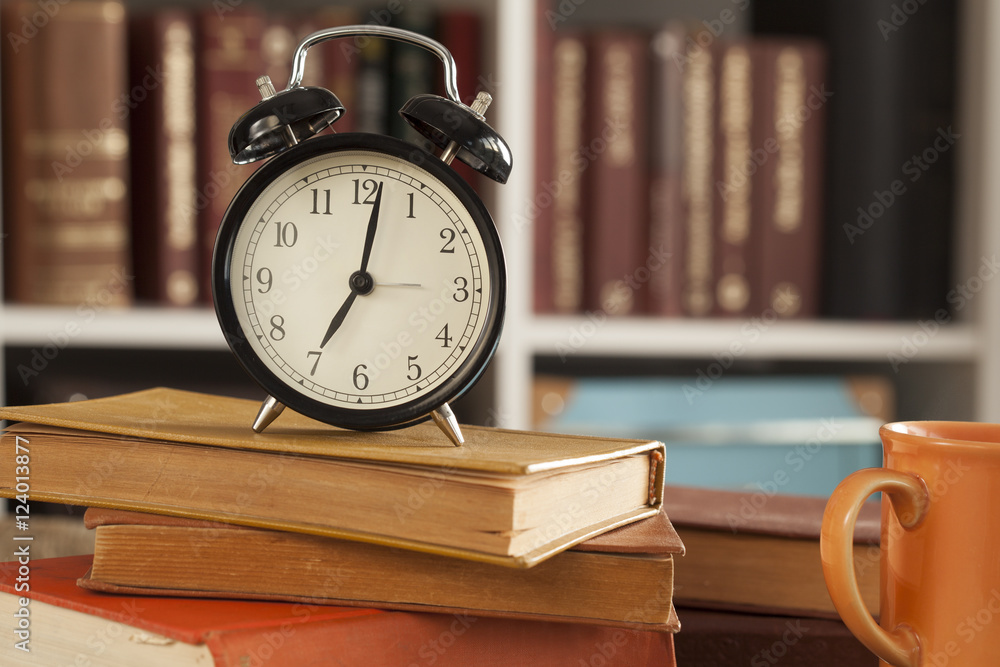 Pile of books with o'clock on desk Pile of books with o'clock on desk