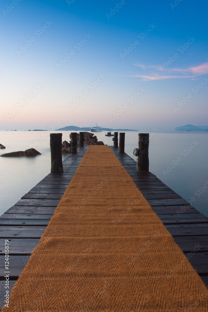 Sunrise on the beach.Wooden pier in Romazzino, Sardinia, Italy