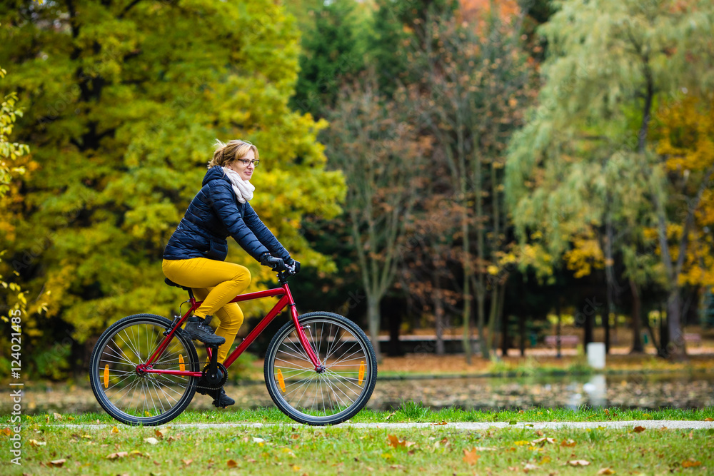 Urban biking - woman riding bike in city park 