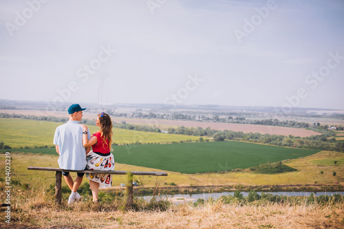 Cute couple sitting on bench together smiling at each other on a sunny day