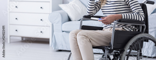Woman sitting on a wheelchair with the pregnancy test in her hand