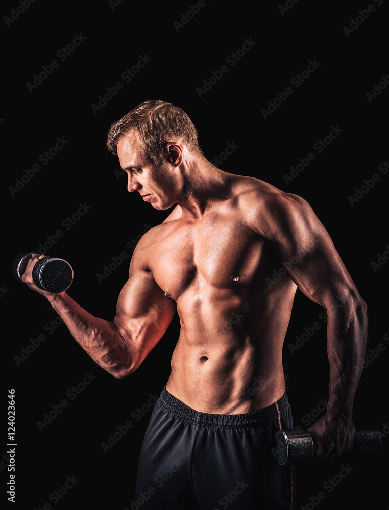 Muscular man working out doing exercises with dumbbells at biceps