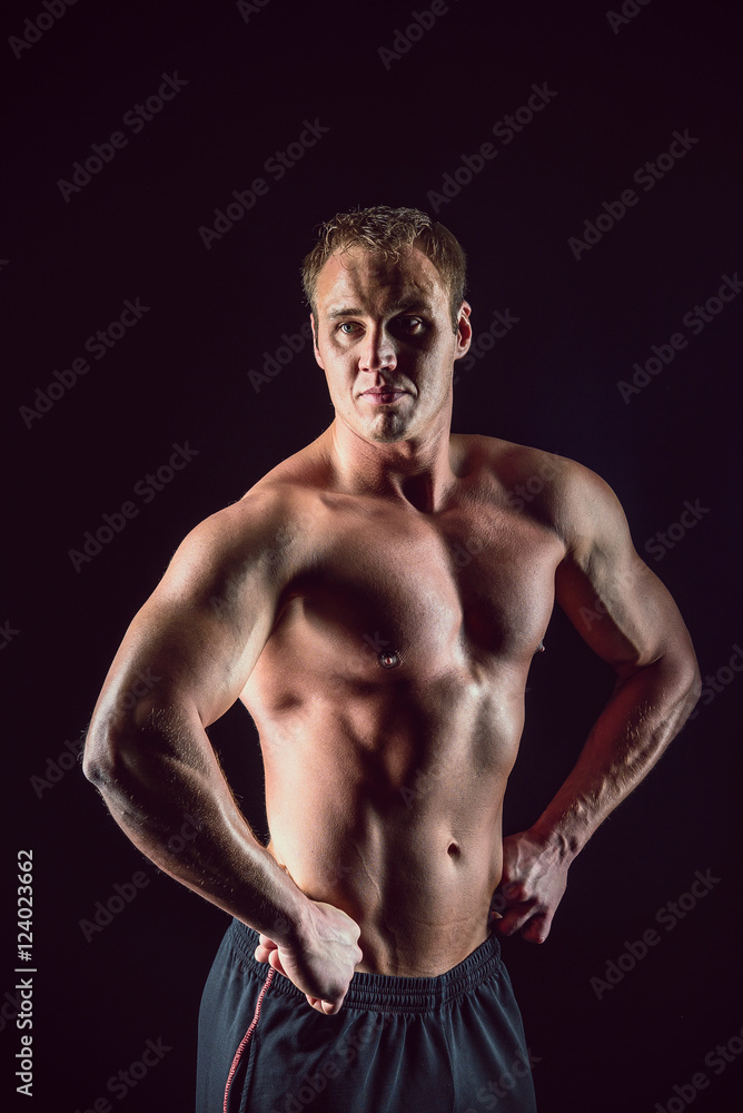 Sporty and healthy muscular strong man isolated on black background