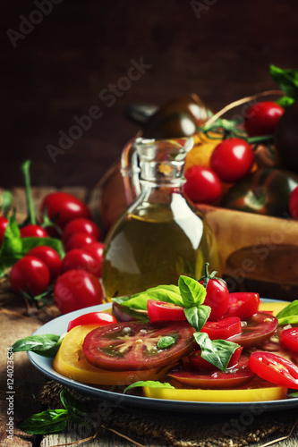 Salad of colorful tomatoes on plate. Vintage wooden background,
