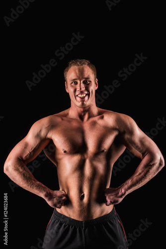 Sporty and healthy muscular strong man isolated on black background smiling