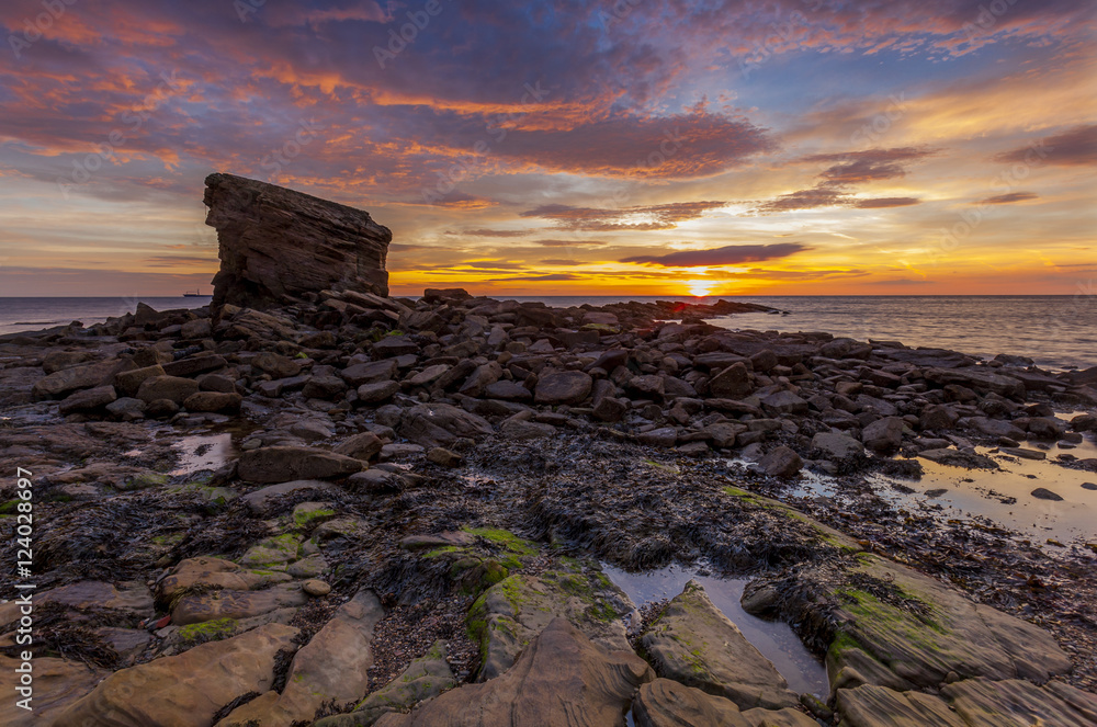 Sunrise over Charlies Garden, and rocks at Collywell Bay, Seaton Sluice, Northumberland, England, UK.
