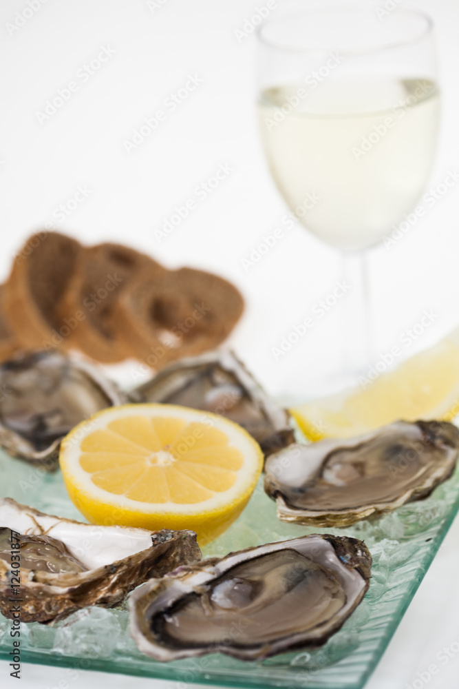 assiette d'huîtres avec un verre de vin blanc et une tranche de citron  Stock Photo | Adobe Stock