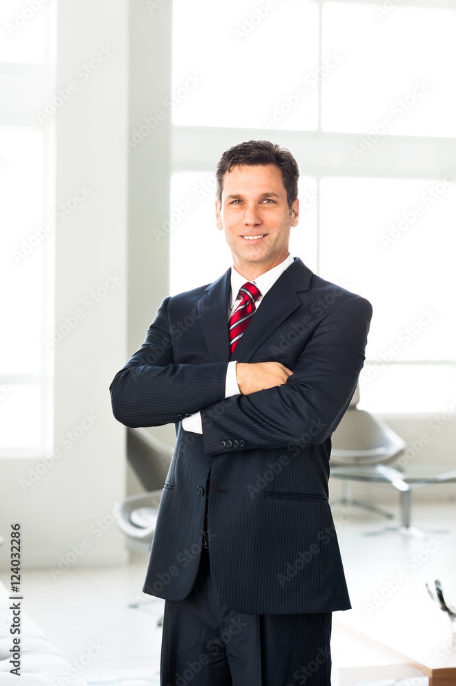 Businessman with arms crossed in office lobby Businessman with arms crossed in office lobby