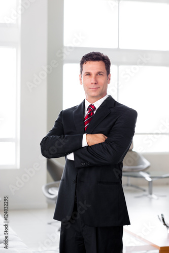 Businessman with arms crossed in office lobby