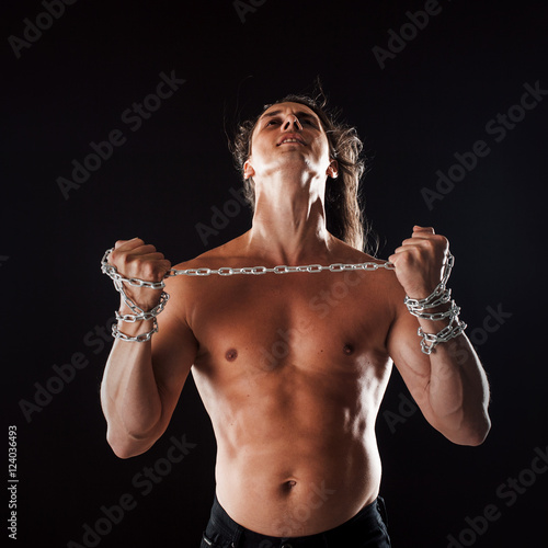 Young man with long hair breaks the iron chain. Strong. Concept of resistance © Ulia Koltyrina