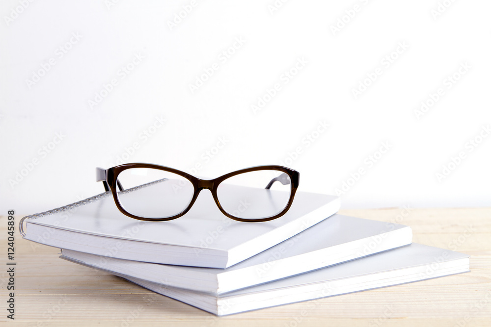 pile of exercise books and glasses on a white background and a wooden table. learning pile of exercise books and glasses on a white background and a wooden table. learning