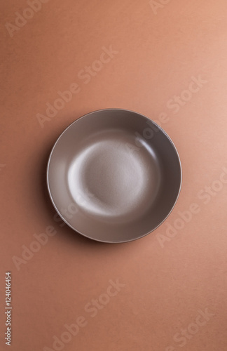 Brown plate on brown background,above view.Useful as a food back