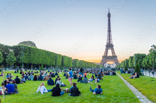 Eiffel Tower and people sitting on the grass watching sunset in Paris, France
