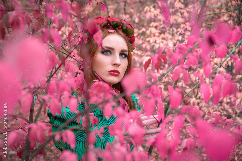A beautiful and fabulous girl in a pink foliage with red wreath