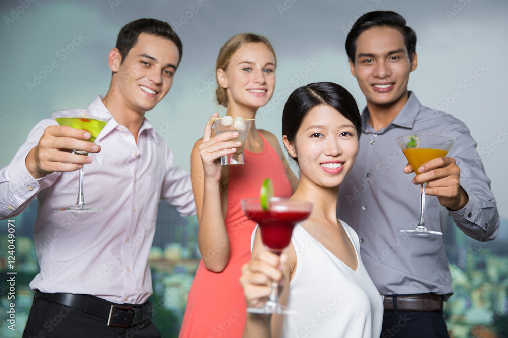 Four Smiling People with Cocktails Toasting in Bar