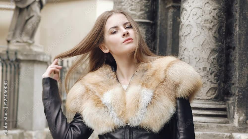 Cute girl flirting in furry jacket and posing on the street. Slowly Cute girl flirting in furry jacket and posing on the street. Slowly