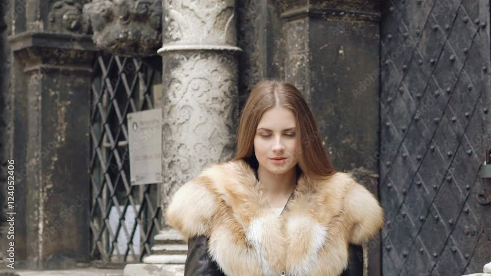 Cute girl flirting in furry jacket and smiling on the street. Slowly Cute girl flirting in furry jacket and smiling on the street. Slowly