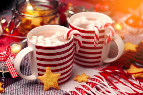 Christmas cups with hot chocolate and marshallow. Red plaid, ginger peonie in the form of stars, glowing lights. Vintage Christmas toys. photo