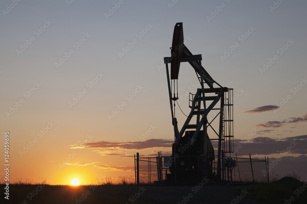 Silhouette Of Pump Jack With The Orange Glow Of The Sun Rising On The Horizon; Longview,Alberta, Canada Silhouette Of Pump Jack With The Orange Glow Of The Sun Rising On The Horizon; Longview,Alberta, Canada
