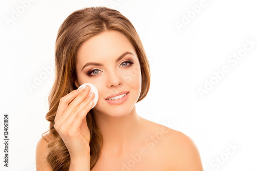Young pretty woman taking off her makeup with cotton wipe