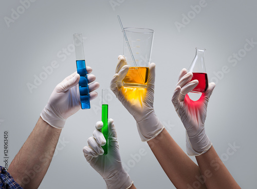 Hands holding laboratory glassware with liquids