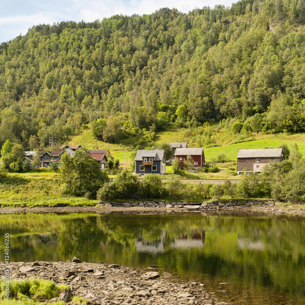 Houses in valley beside tree covered hill and tranquil water, Bergen, Norway