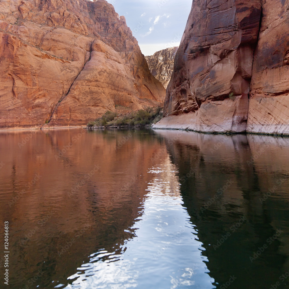 Steep Rock Cliffs Along The Shoreline Reflected In The Colorado River; Arizona, United States of America Steep Rock Cliffs Along The Shoreline Reflected In The Colorado River; Arizona, United States of America