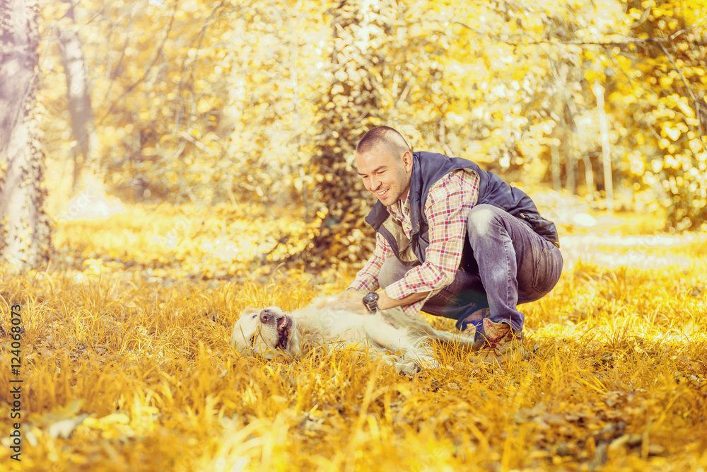 Young man walking a dog at the park in good weather. Boy and golden retriever.
Autumn environment