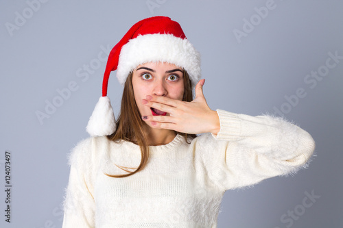 Woman in red christmas hat hiding her mouth