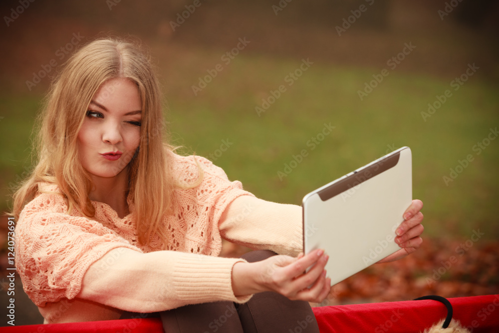 Obraz premium Girl sitting on bench with tablet.