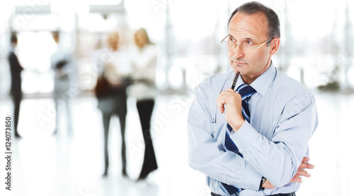 portrait of a thinking businessman on background of office. photo has free space for your text