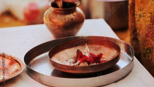 Hindu woman puts red petals on bronze plate