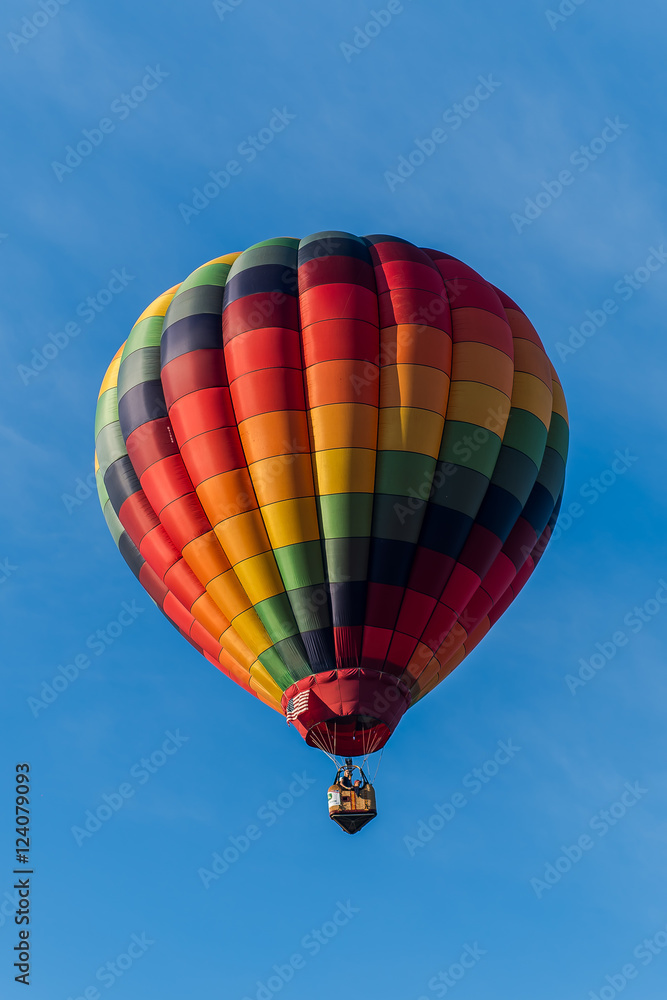This is a photo of a beautiful hot air balloon slowly sailing through a calm blue sky. This is a photo of a beautiful hot air balloon slowly sailing through a calm blue sky.
