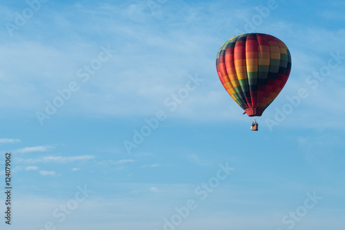 This is a photo of a beautiful hot air balloon slowly sailing through a calm blue sky. © jeremydeihl