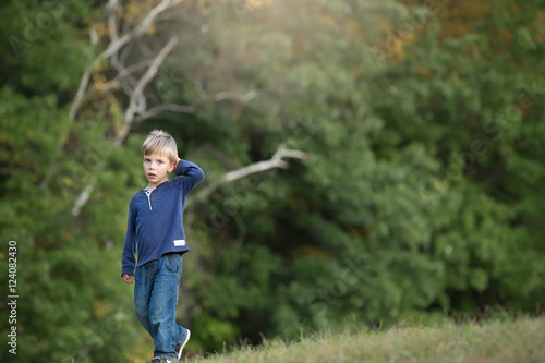 blonde boy walking alone and sad in the woods