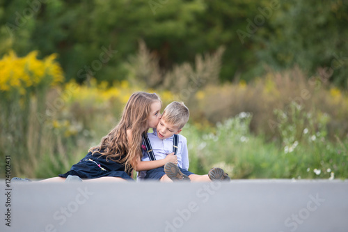 boy and girl sitting on a sidewalk and kissing
