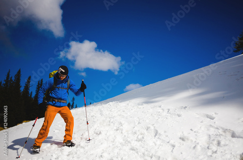 Mountain climber walks on a snowy slope.