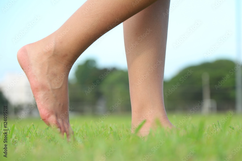 Woman walking barefoot on grass.