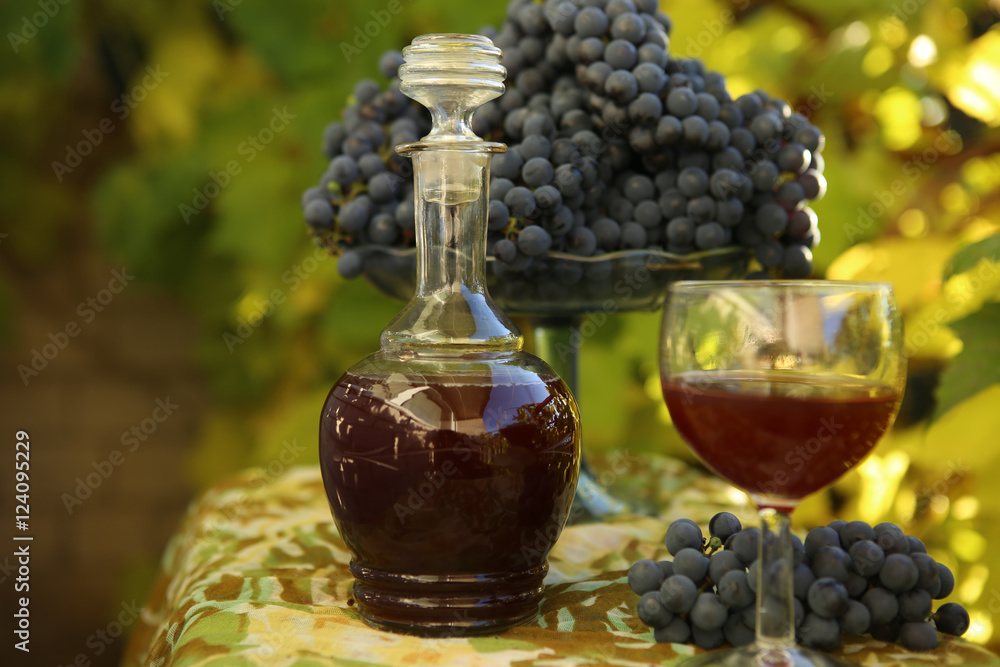 Homemade wine from grapes. Decanter, glass, grapes  photographed against the background of the vine. 